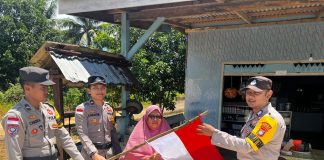 Satukan Semangat Kemerdekaan, Bhabinkamtibmas Polres Natuna Bagikan dan Ajak Warga Kibarkan Merah Putih