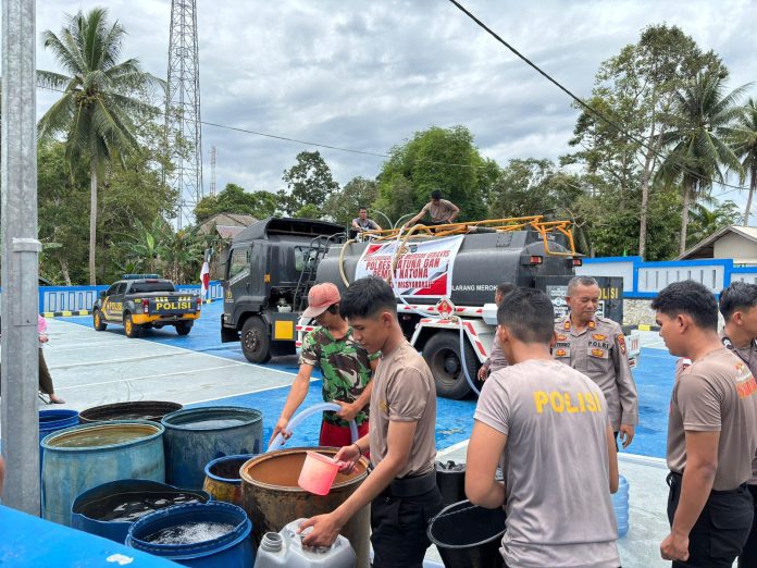 Personil polres natuna menyalurkan air bersih di Desa Binjai